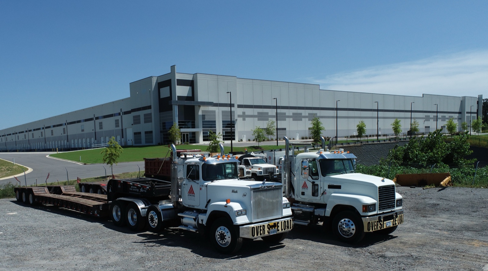 Two Jenkins trucks parked outside a large warehouse