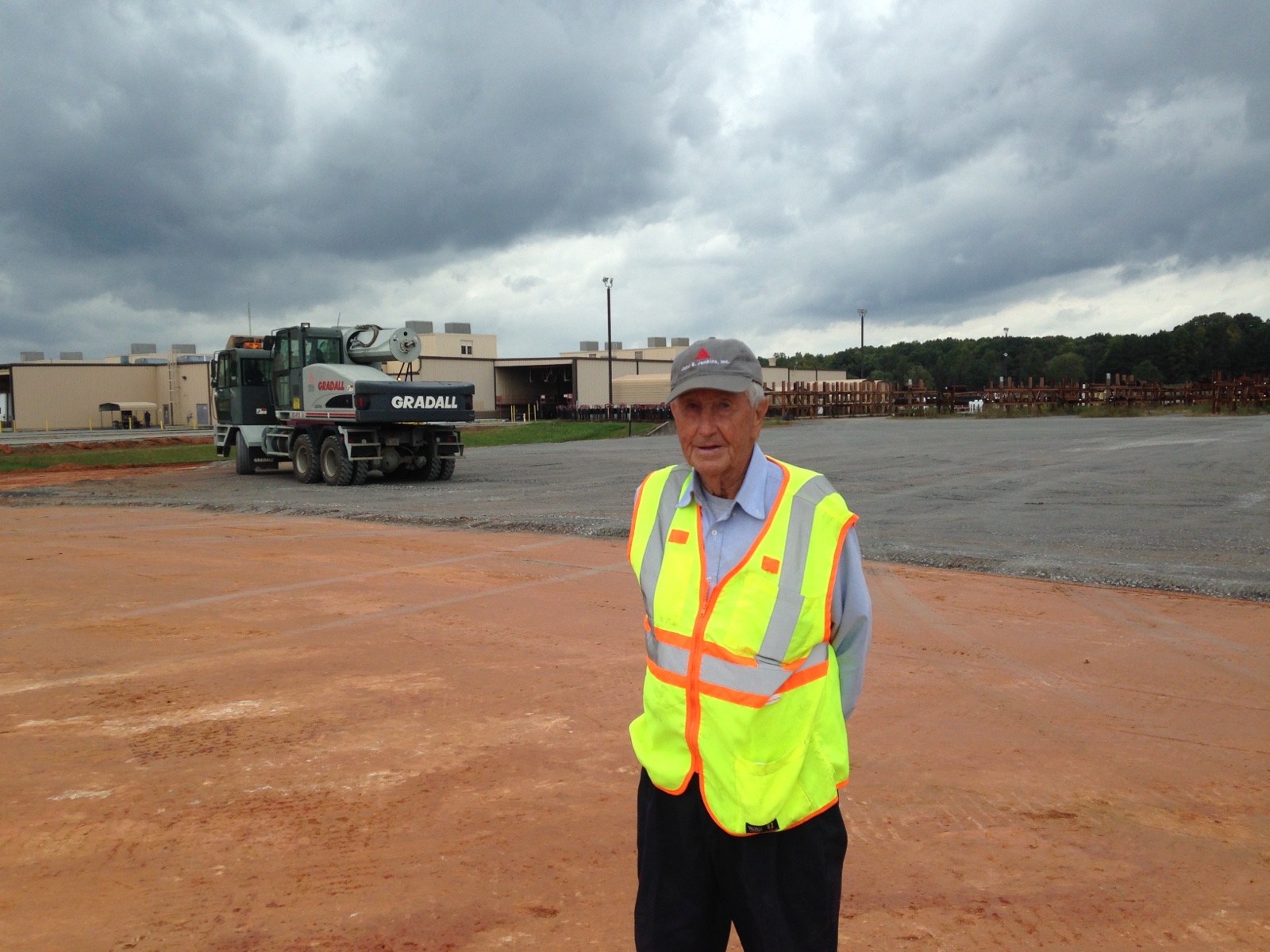 A Jenkins family leader on a graded Jenkins jobsite, equipment and storm sky behind him