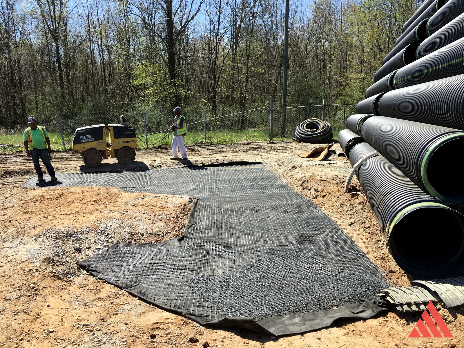 Geogrid installation beside ADS pipe inventory during industrial yard work
