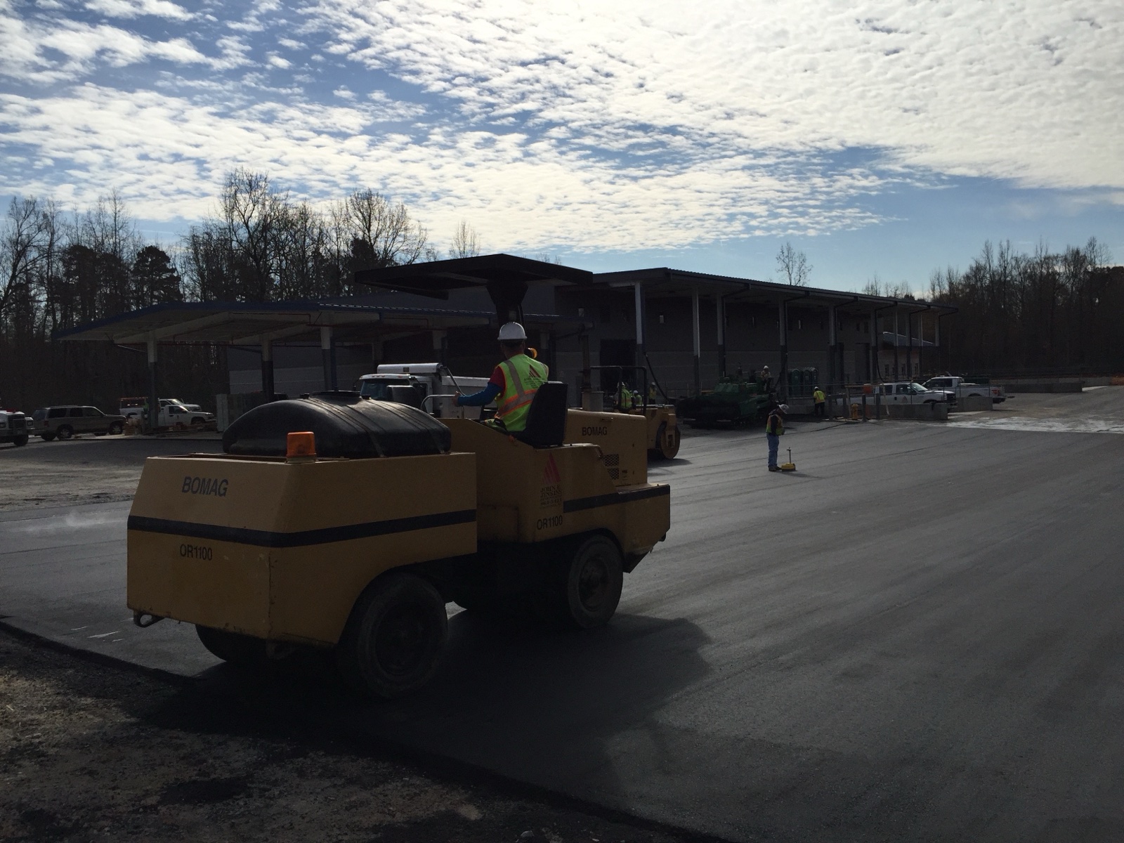 Jenkins crew compacting fresh asphalt with a BOMAG roller